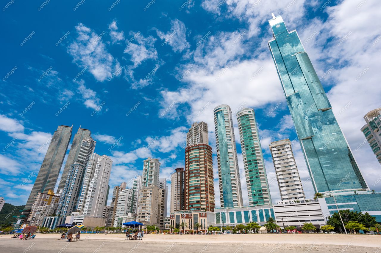Balneário Camboriú, Santa Catarina, vista da praia com arranha-céus variados sob céu azul e nuvens brancas