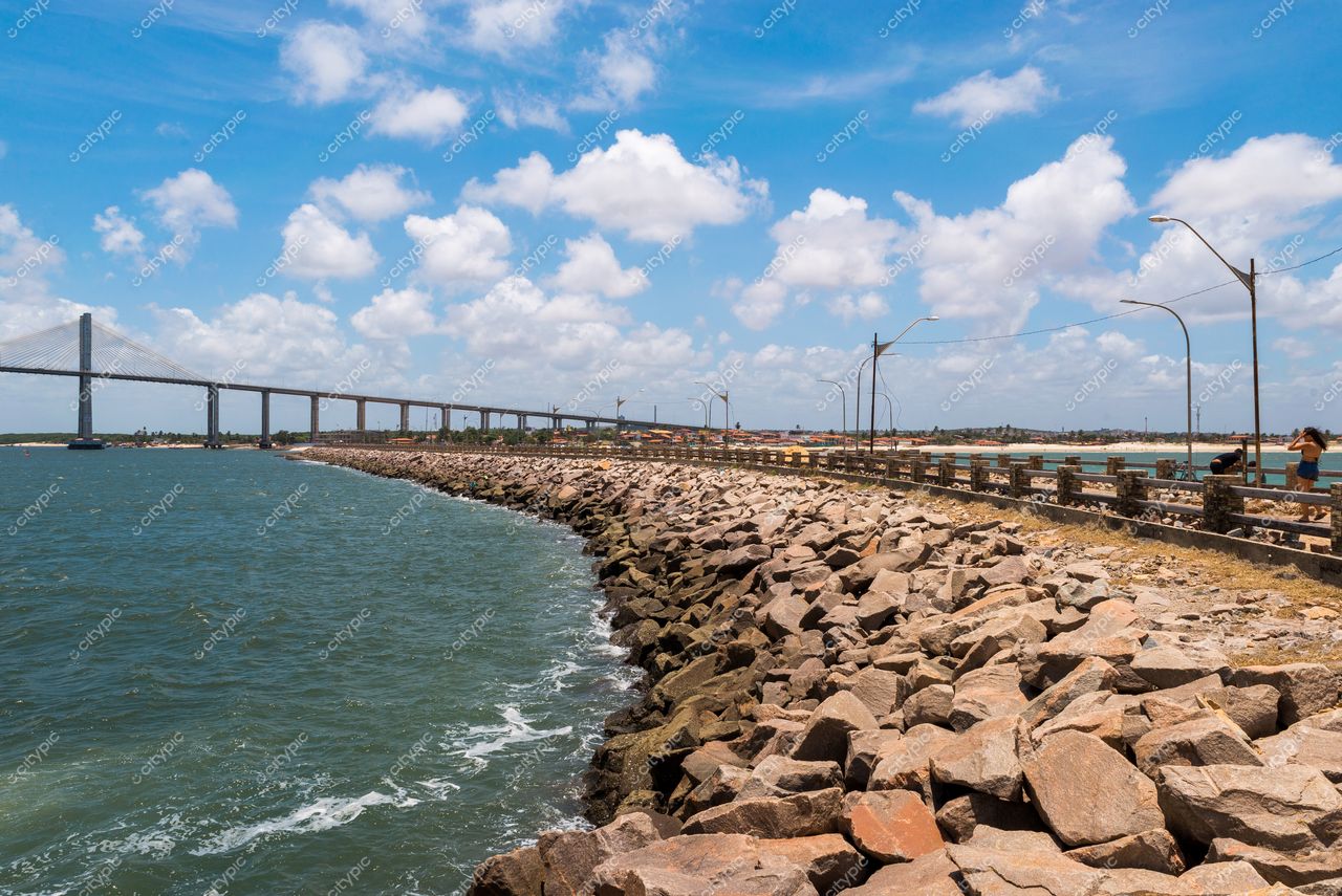 Natal, Rio Grande do Norte com píer de pedras e ponte ao fundo em dia ensolarado e céu claro