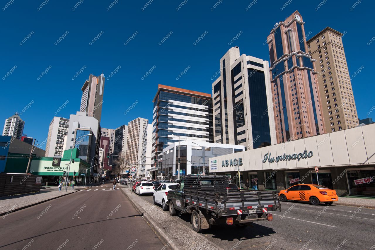 Curitiba, Paraná vista urbana em dia ensolarado com prédios modernos e tráfego leve de veículos na rua ampla