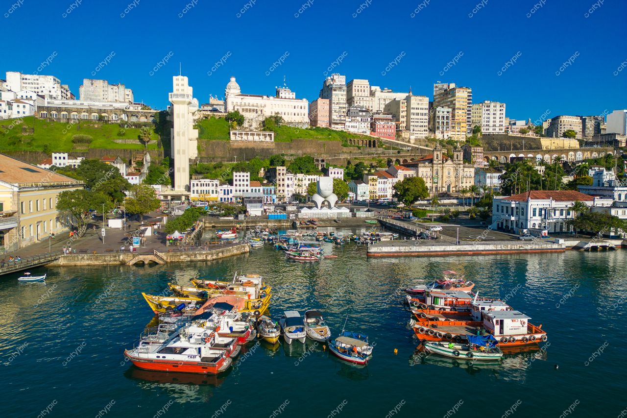 Salvador, Bahia com embarcações coloridas ancoradas em baía tranquila e edifícios históricos sob céu azul claro