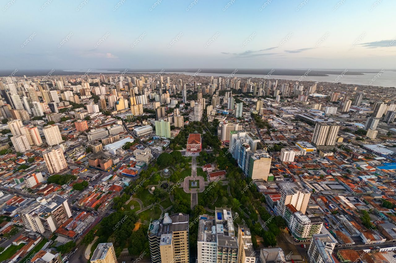Belém, Pará vista aérea ao entardecer com edifícios altos, parques verdes e o rio próximo à cidade