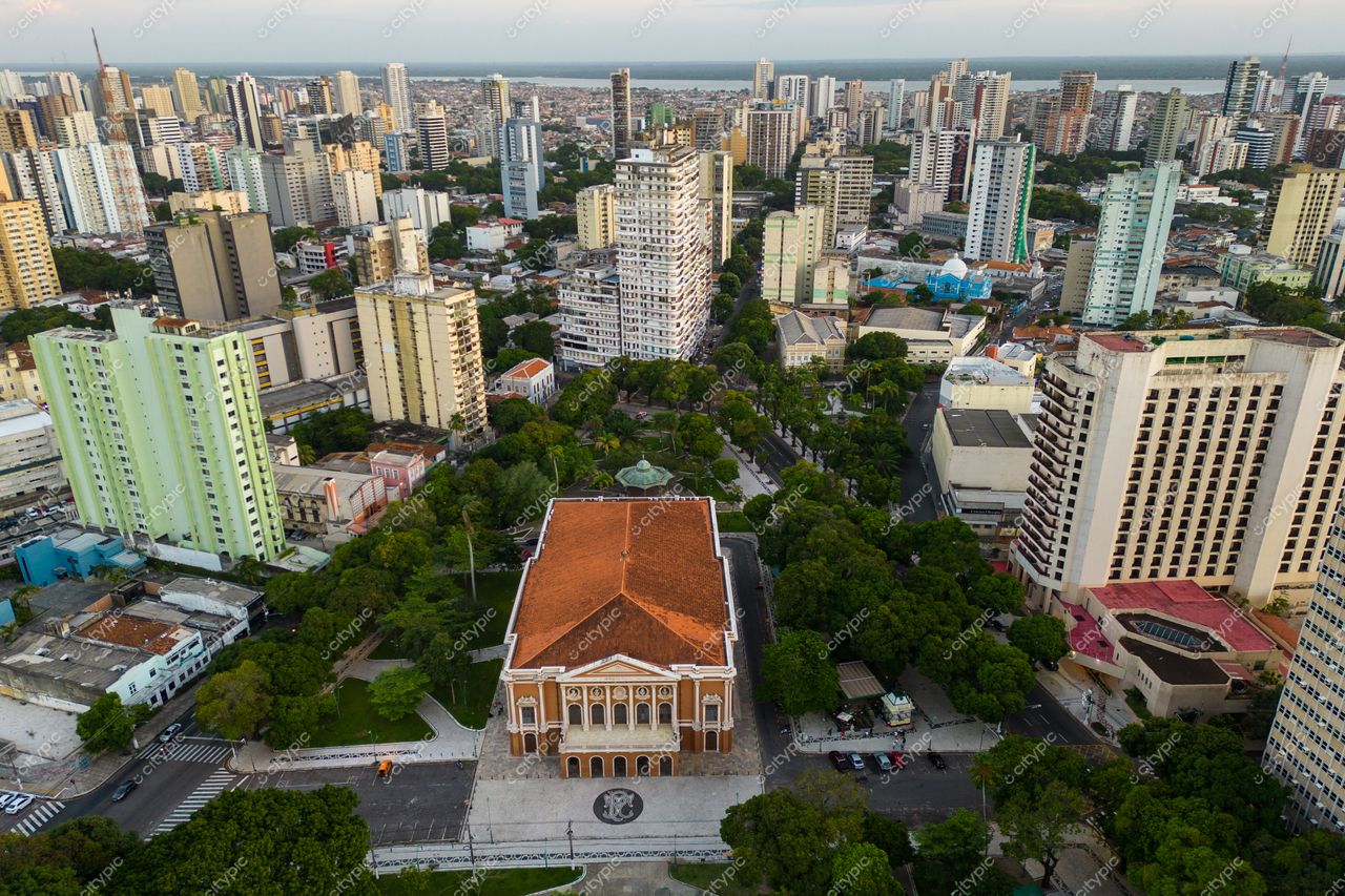 Belém, Pará vista aérea com prédio histórico de telhado laranja cercado por vegetação e torres modernistas ao entardecer