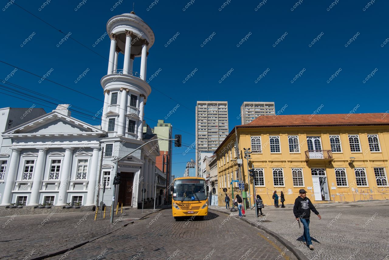 Curitiba, Paraná vista urbana em dia ensolarado com ônibus amarelo e edifícios históricos distintos ao fundo