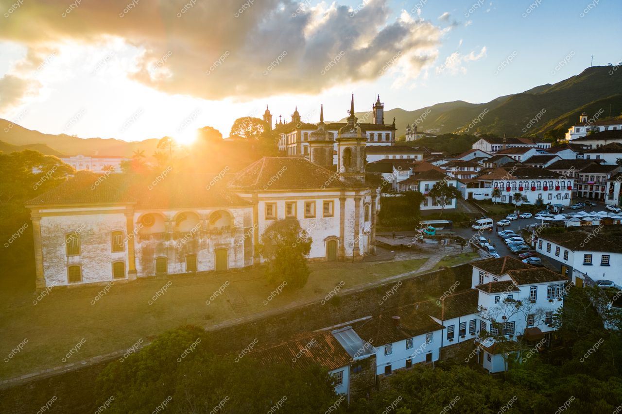 Ouro Preto, Minas Gerais ao entardecer com luz solar entre nuvens e arquitetura colonial em relevo montanhoso