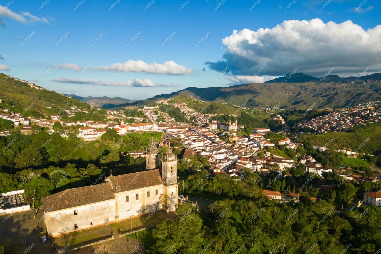 Ouro Preto, Minas Gerais vista aérea com igreja barroca em primeiro plano e montanhas ao fundo sob céu azul