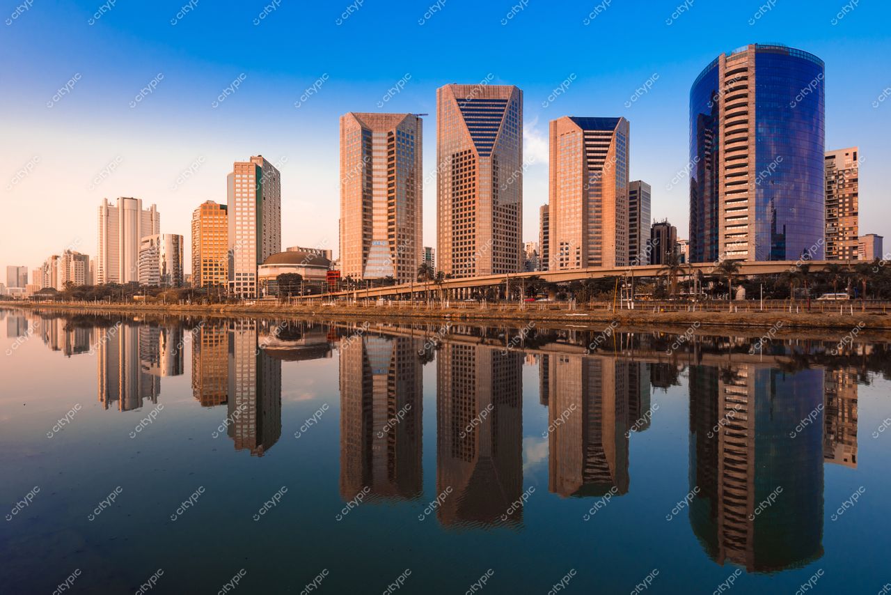 São Paulo, São Paulo, vista de arranha-céus modernos refletindo em lago sob céu azul próximo ao pôr do sol