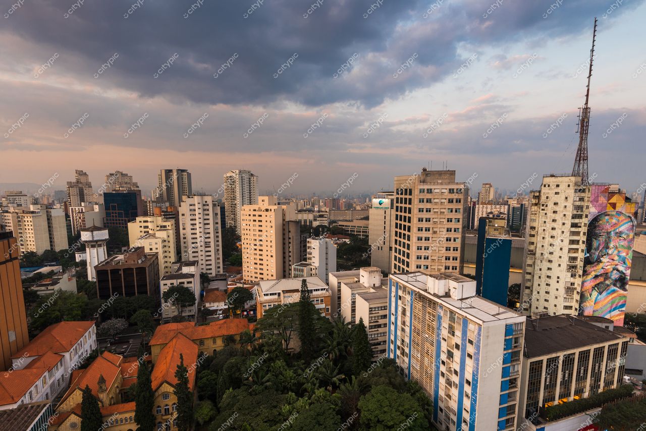 São Paulo, São Paulo, vista panorâmica ao entardecer com céu nublado e mistura de arquitetura moderna e vegetação urbana