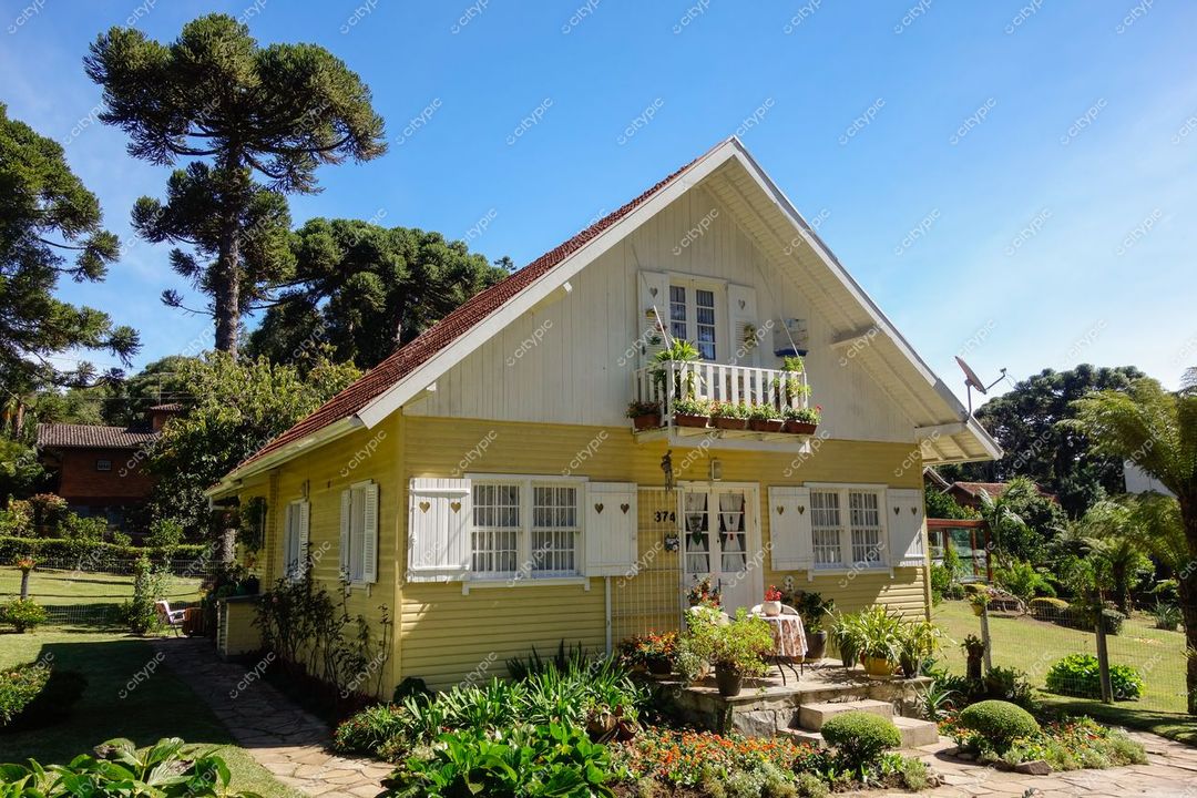 Gramado, Rio Grande do Sul, casa de madeira amarela com varanda e jardim florido em dia ensolarado