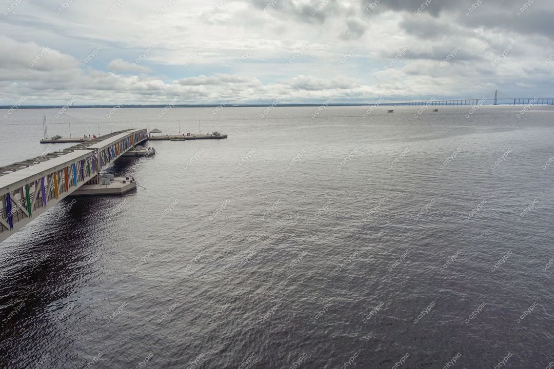 Manaus, Amazonas, pier sobre águas calmas com céu nublado e ponte ao fundo em ambiente de lazer