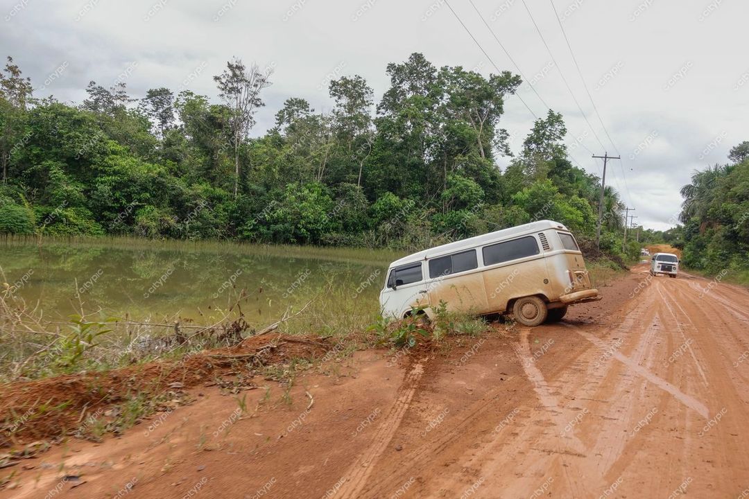 Manaus, Amazonas, veículo utilitário branco em estrada de terra vermelha com vegetação densa e céu nublado ao fundo