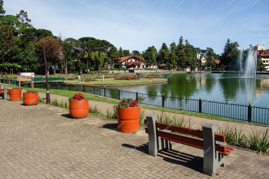 Gramado, Rio Grande do Sul vista do Lago Negro com árvores altas, banco de madeira e flores vibrantes durante o dia