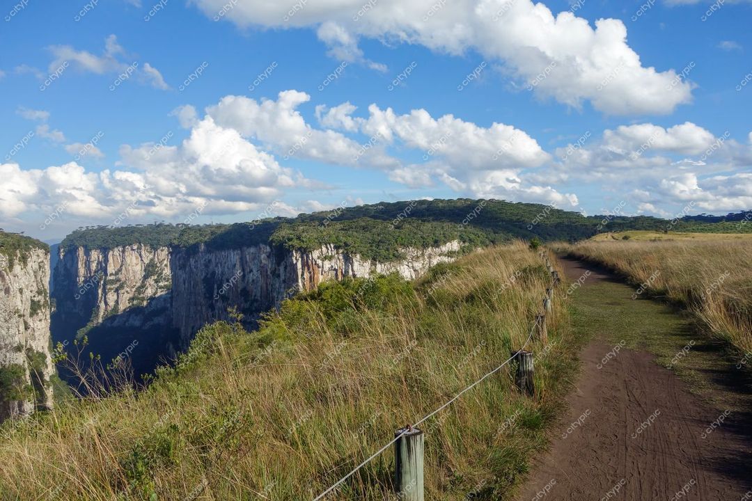 Cambará do Sul, Rio Grande do Sul, trilha de terra com formações rochosas e céu parcialmente nublado durante o dia