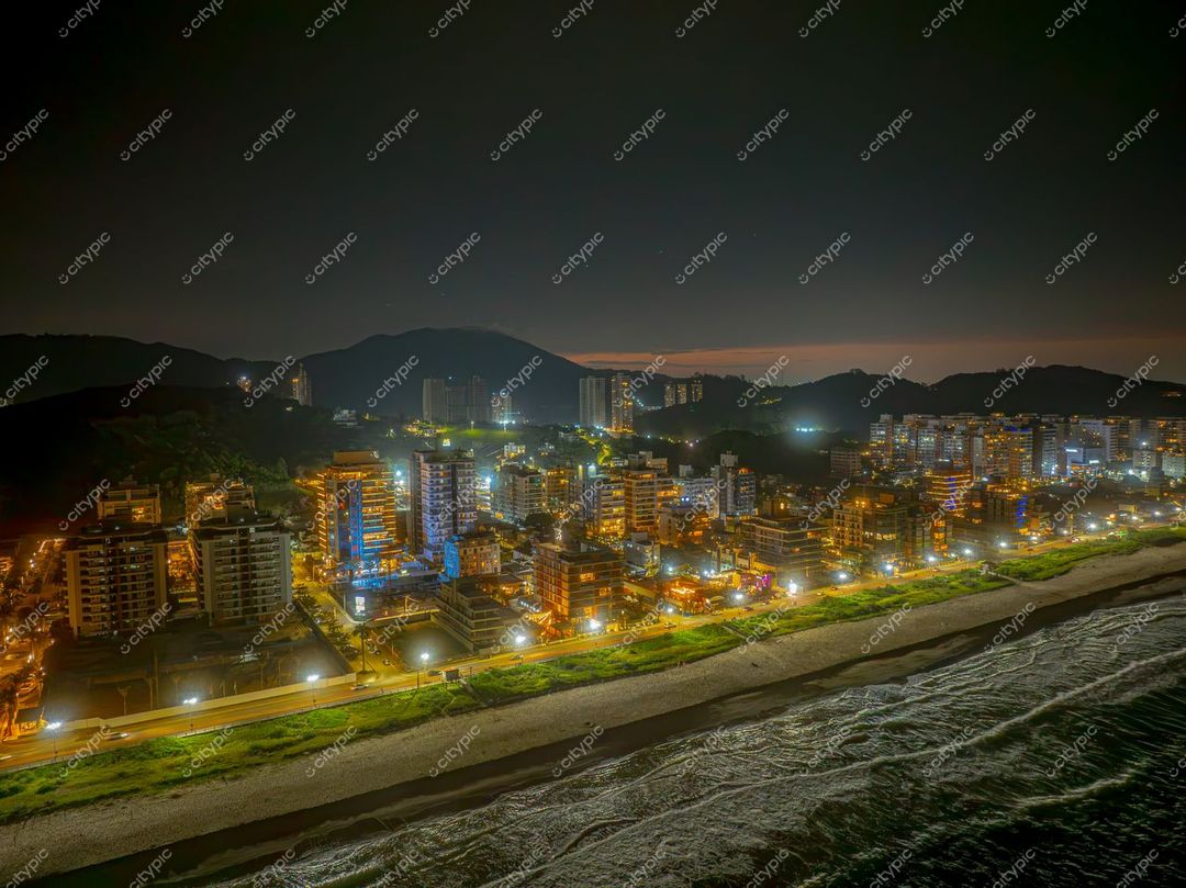 Itajaí, Santa Catarina à noite com edifícios iluminados à beira-mar e montanhas ao fundo em ambiente tranquilo