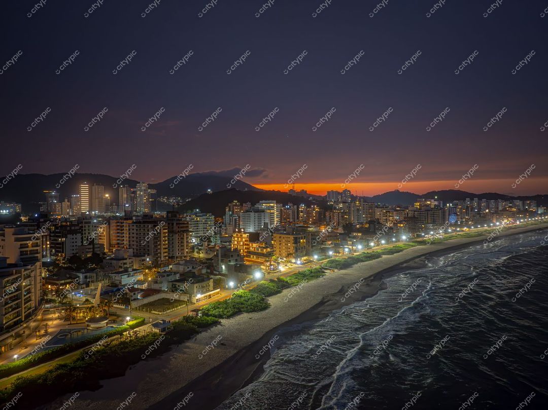 Itajaí, Santa Catarina vista noturna com céu crepuscular e reflexos da iluminação nas ondas do mar