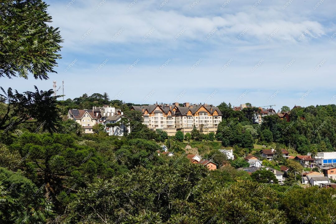 Gramado, Rio Grande do Sul com arquitetura europeia em colina arborizada sob céu parcialmente nublado e vegetação abundante