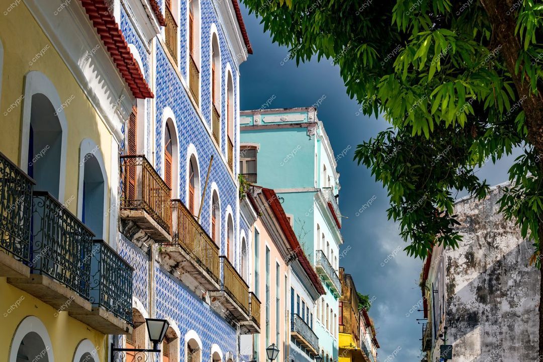 São Luís, Maranhão, rua com arquitetura colonial colorida e céu nublado, destacando varandas e vegetação urbana