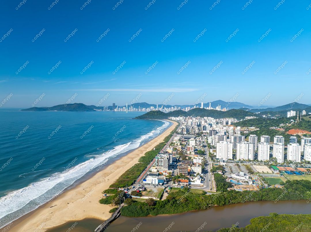 Itajaí, Santa Catarina vista aérea com praia, edifícios residenciais e montanhas verdes sob céu azul em dia ensolarado