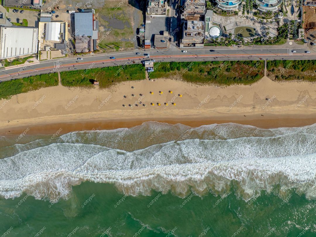 Itajaí, Santa Catarina vista aérea da praia com vegetação, calçadão, cadeiras e guarda-sóis em dia claro