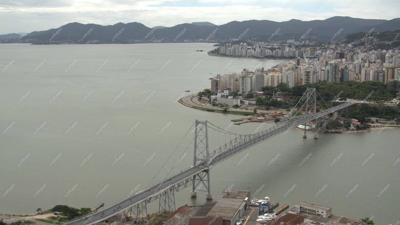Centro de Florianópolis com vista da ponte, montanhas ao fundo e céu nublado em dia tranquilo