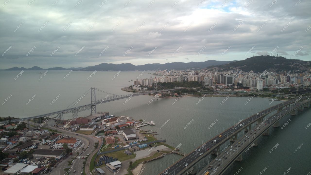 Centro, em Florianópolis, vista aérea em dia nublado com ponte, prédios alinhados e vegetação ao redor