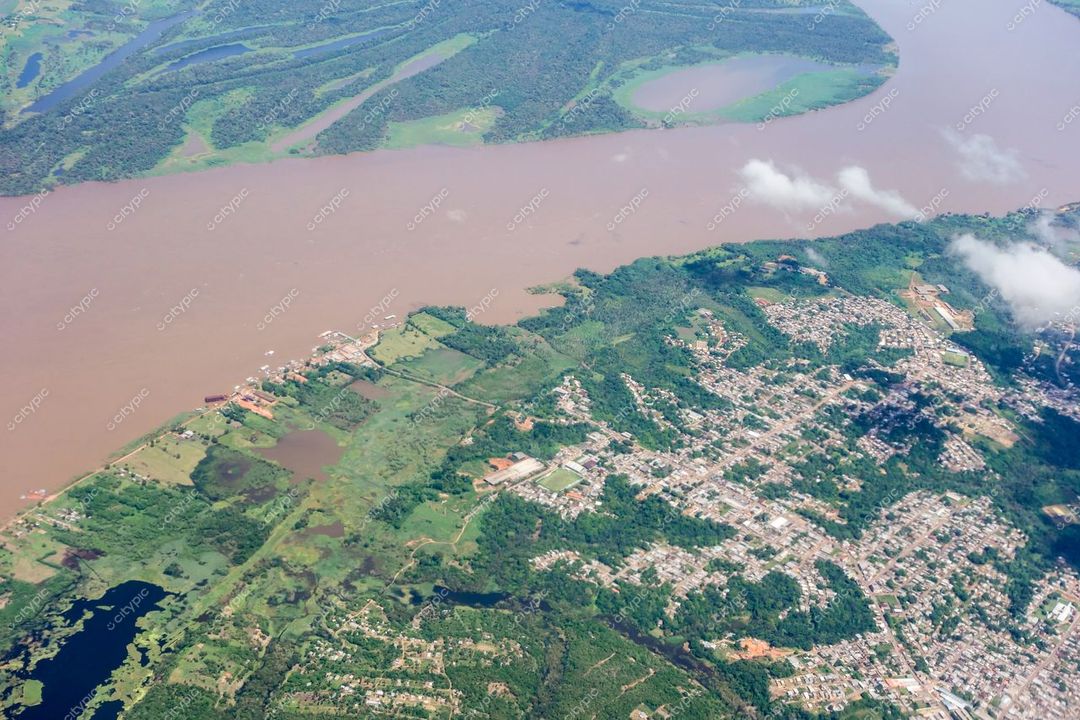 Manaus, Amazonas vista aérea com contraste entre rio marrom e áreas urbanas cercadas por vegetação densa em dia claro