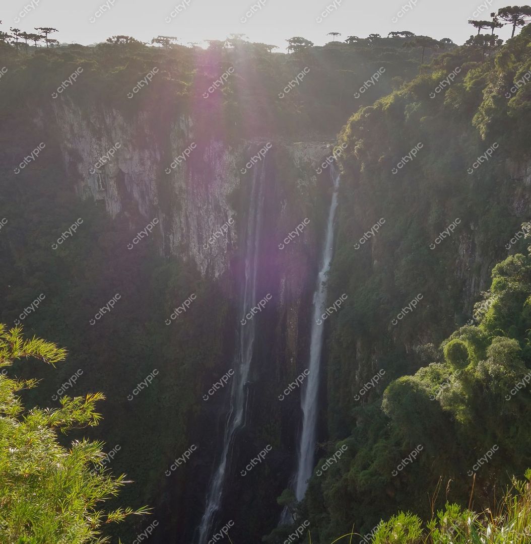 Cambará do Sul, Rio Grande do Sul, queda d’água iluminada pelo sol poente em meio a montanhas e vegetação densa