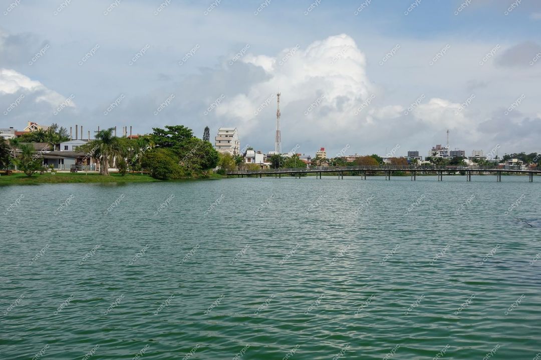 Torres, Rio Grande do Sul, cenário urbano à beira do lago com edificações e vegetação sob céu nublado