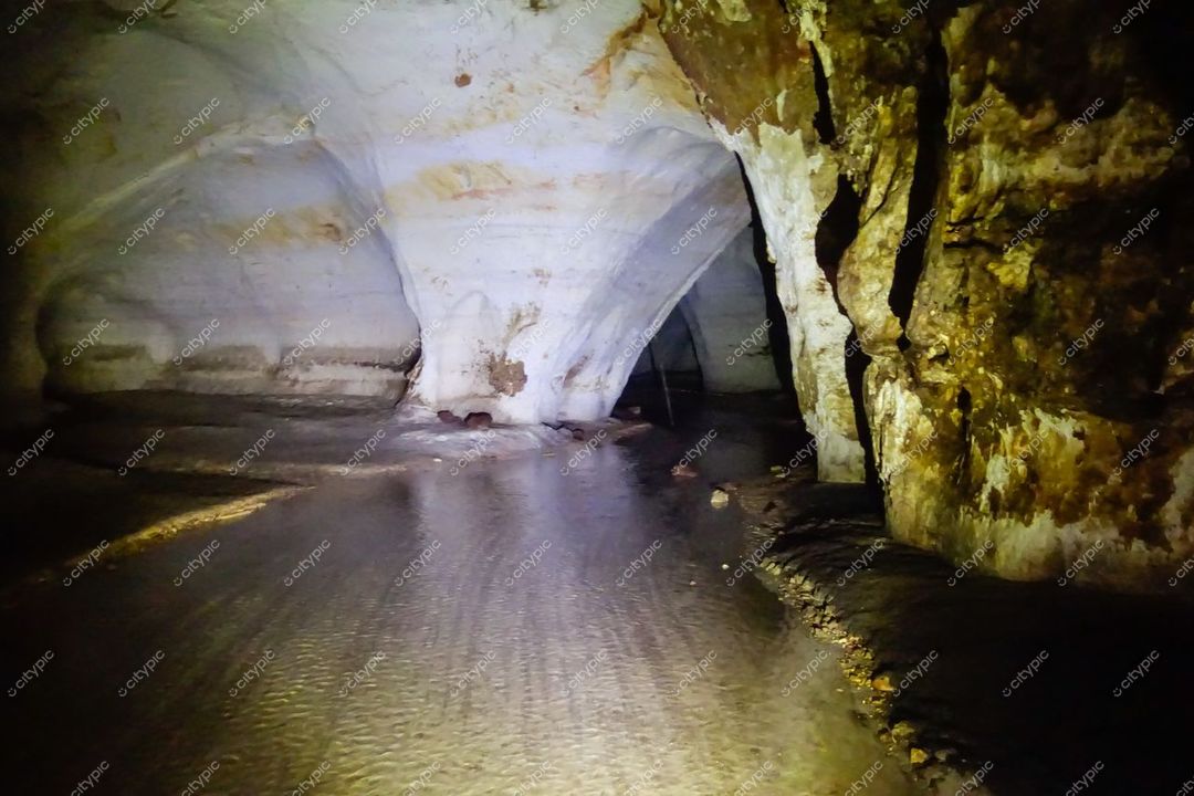 Presidente Figueiredo, Amazonas, interior de caverna com formações rochosas e leito de água refletindo luz suave