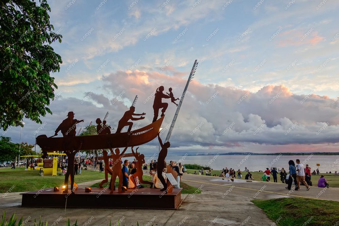 Porto Alegre, Rio Grande do Sul, pôr do sol iluminando escultura de metal em canoa no calçadão do Guaíba