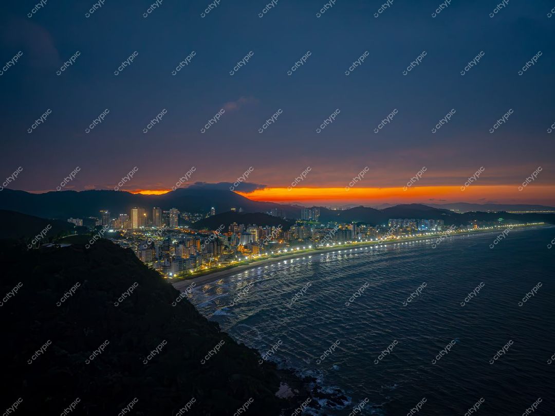 Itajaí, Santa Catarina, orla ao crepúsculo com reflexos de luzes urbanas e montanhas ao fundo