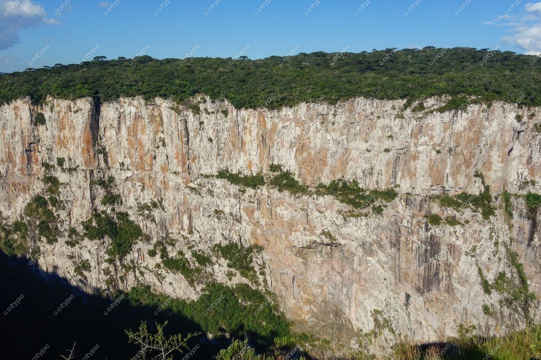 Cambará do Sul, Rio Grande do Sul, penhasco com tons de laranja e cinza sob luz natural diurna e vegetação densa