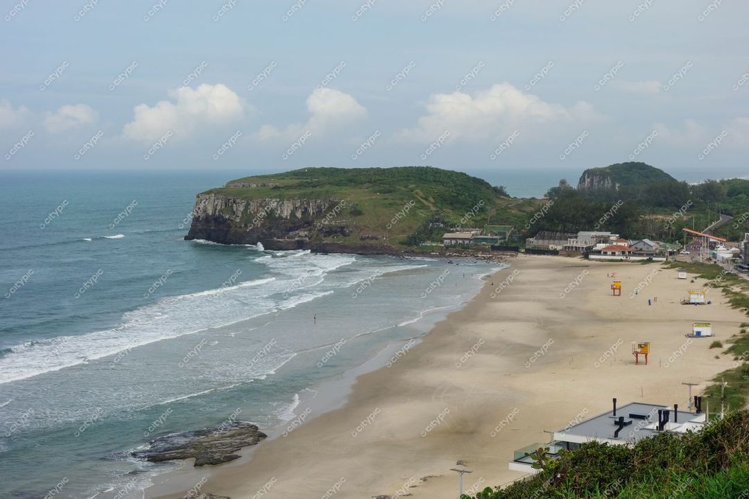 Torres, Rio Grande do Sul com praia de areia clara, colinas verdes e construções à beira-mar em dia nublado