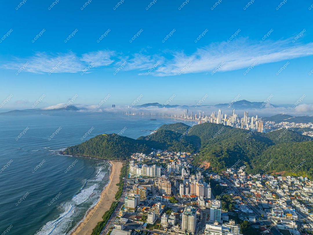 Itajaí, Santa Catarina vista aérea com praias, áreas urbanas organizadas e montanhas sob céu claro e ensolarado