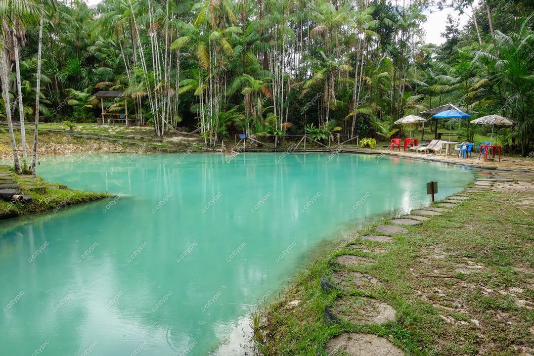Presidente Figueiredo, Amazonas, lago esverdeado cercado por vegetação tropical e área de descanso com mesas coloridas