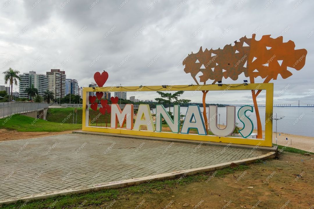 Manaus, Amazonas, letreiro colorido à beira do rio com prédios ao fundo em dia nublado e iluminação suave