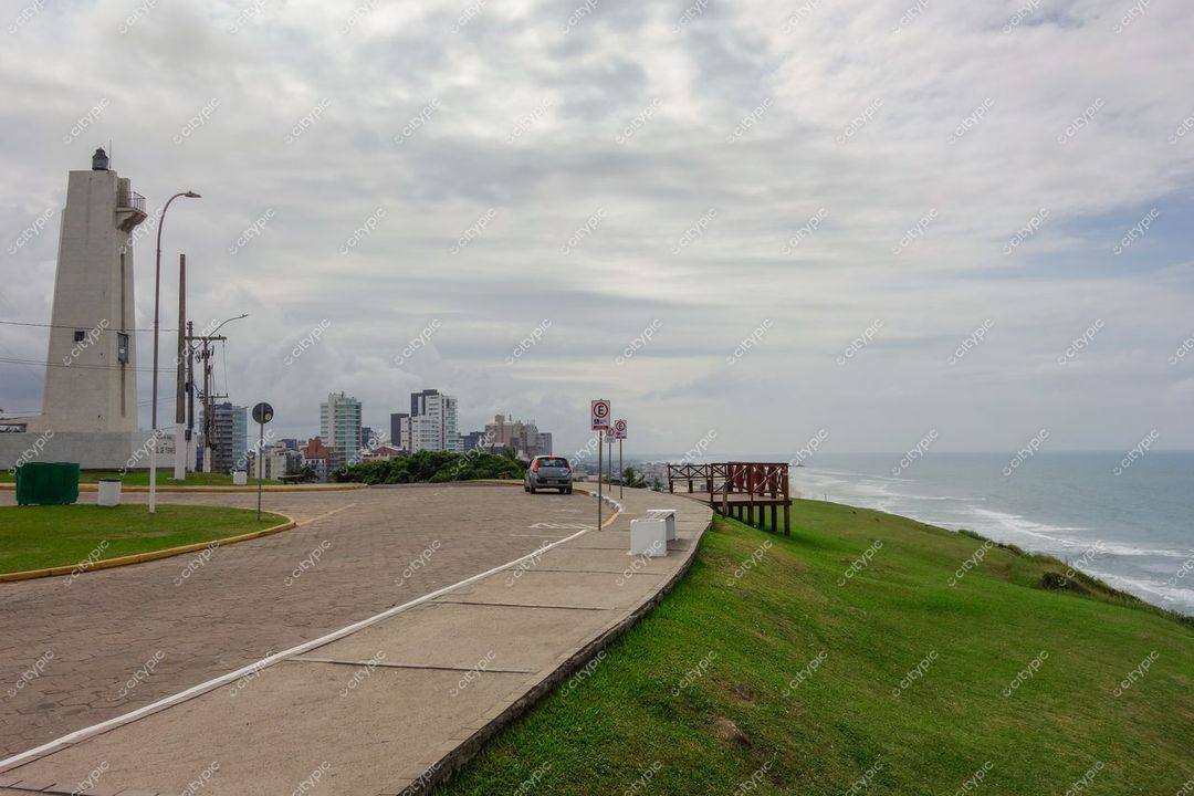 Torres, Rio Grande do Sul, orla marítima com mar calmo, céu nublado e edifícios altos ao fundo