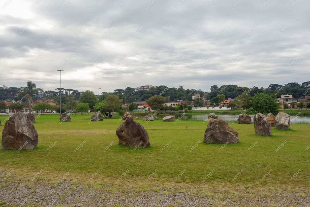 Canela, Rio Grande do Sul, espaço aberto com rochas sobre grama, vegetação variada e céu nublado