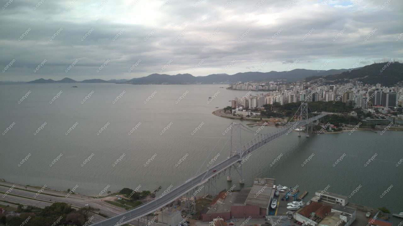 Centro de Florianópolis com vista da Ponte Hercílio Luz em dia nublado e água tranquila na baía