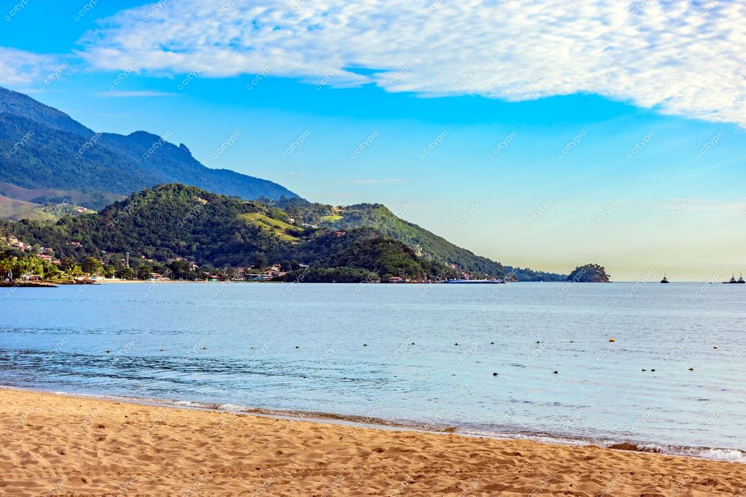 Ilhabela, São Paulo vista tranquila da costa com areia, mar calmo e montanhas verdes sob céu azul claro