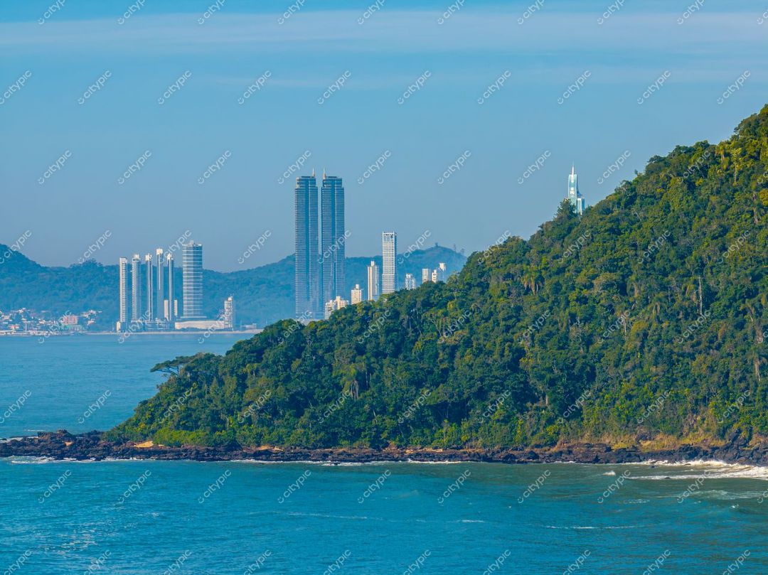 Itajaí, Santa Catarina, vista da costa com mar tranquilo, edifícios modernos e colinas verdes sob luz natural do dia