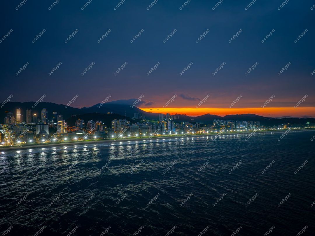 Itajaí, Santa Catarina ao entardecer com céu colorido e reflexos na baía, destacando a arquitetura urbana e montanhas