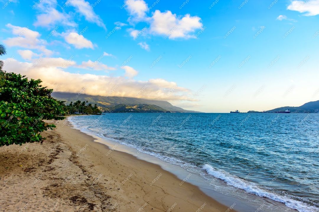 Ilhabela, São Paulo praia tranquila com areia clara e água azulada sob céu azul suave e montanhas ao fundo