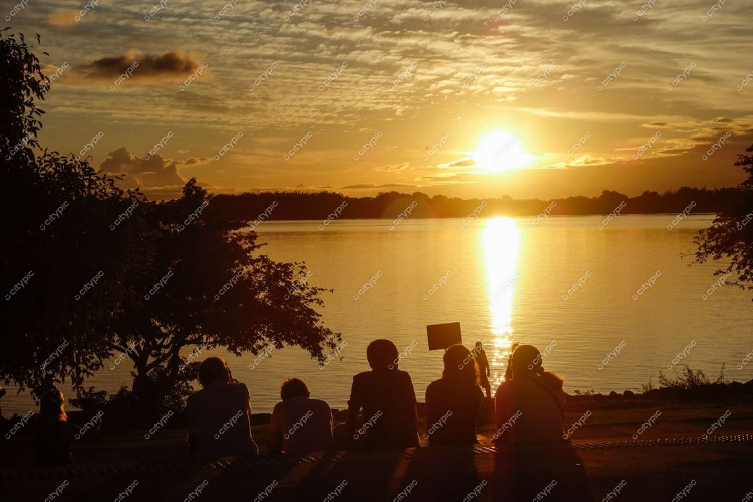 Porto Alegre, Rio Grande do Sul, grupo de pessoas à beira do lago ao pôr do sol com reflexos dourados