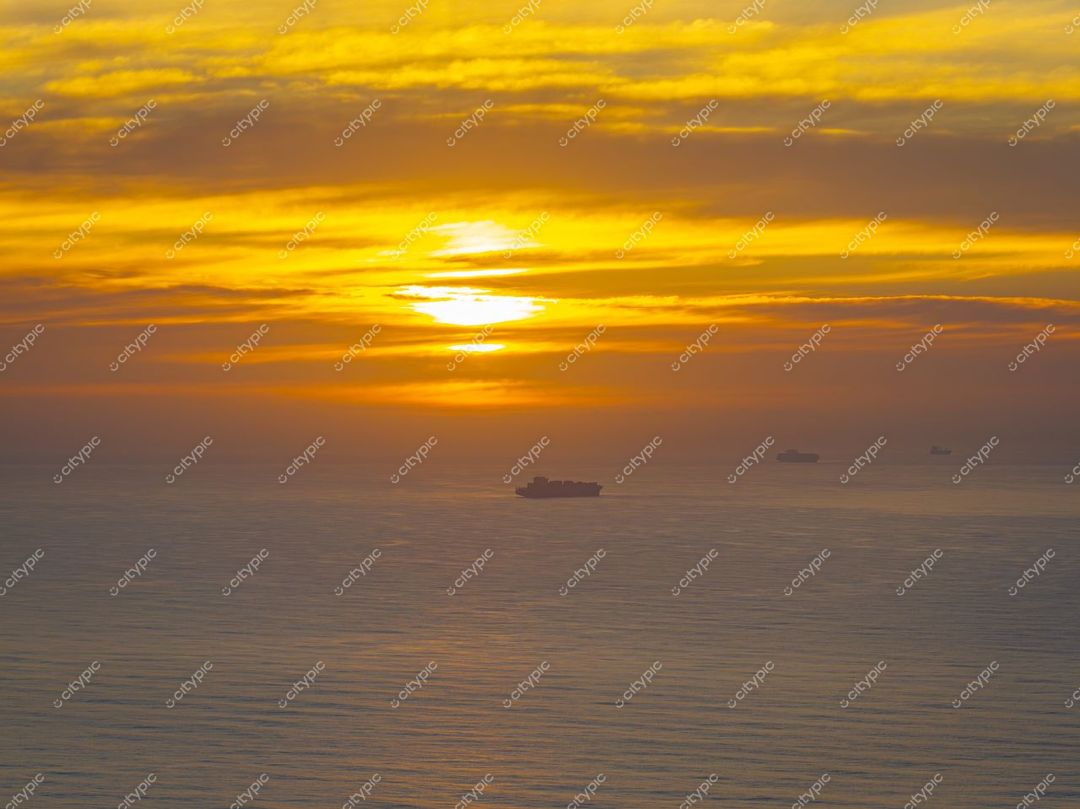 Itajaí, Santa Catarina, pôr do sol dourado refletido no mar com navios de carga ao fundo e céu laranja