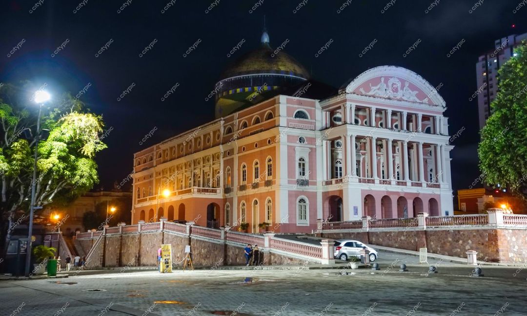 Manaus, Amazonas, Teatro Amazonas iluminado à noite com cúpula dourada e calçada pavimentada em ambiente urbano tranquilo