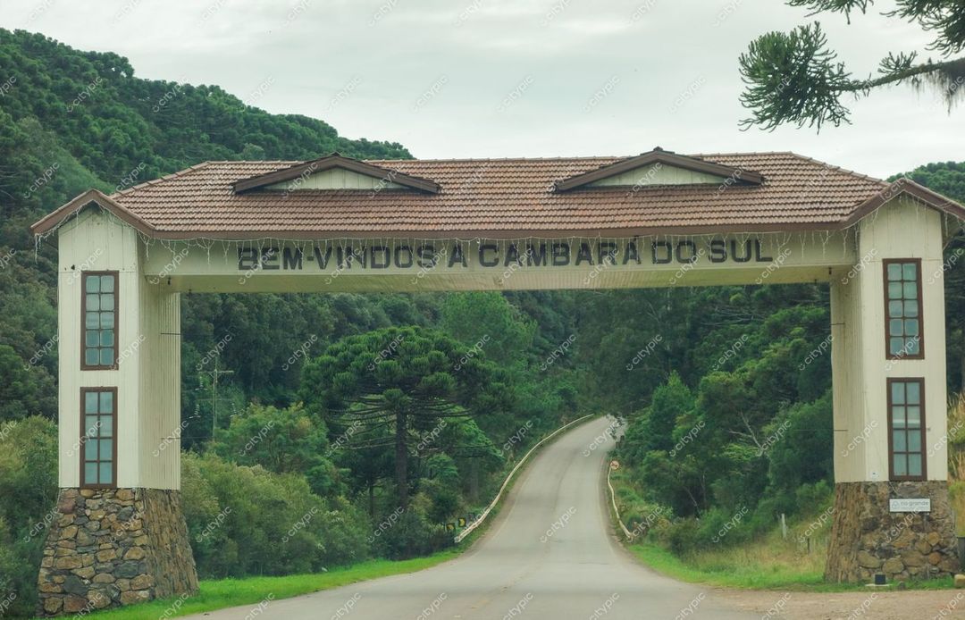 Cambará do Sul, Rio Grande do Sul, arco de entrada em madeira e pedras com vegetação densa e montanhas ao fundo