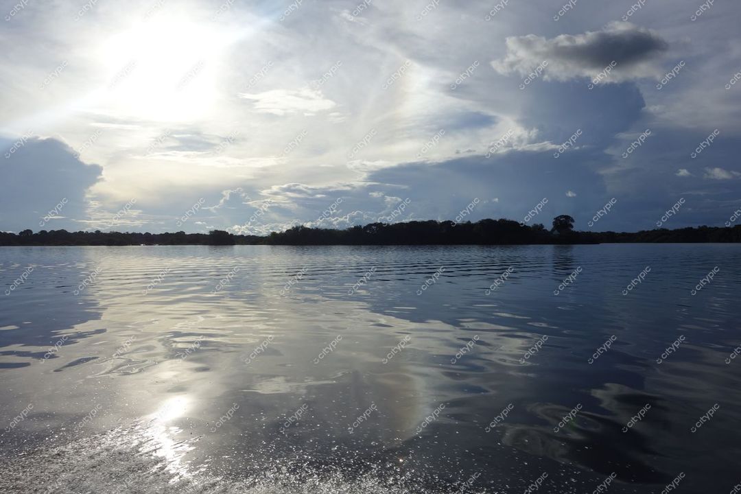 Manaus, Amazonas, reflexos suaves no rio sob céu parcialmente nublado com vegetação densa ao fundo