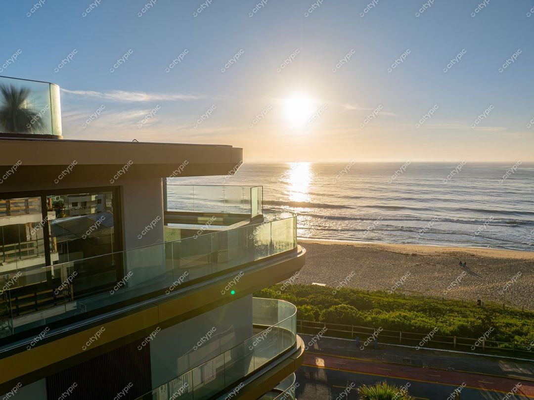 Itajaí, Santa Catarina vista panorâmica ao amanhecer com edifício moderno e vegetação na orla da praia tranquila