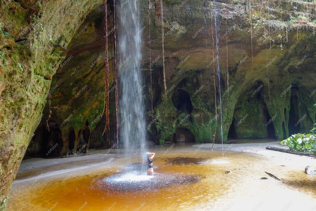 Presidente Figueiredo, Amazonas, cachoeira em caverna com luz natural e vegetação abundante ao redor