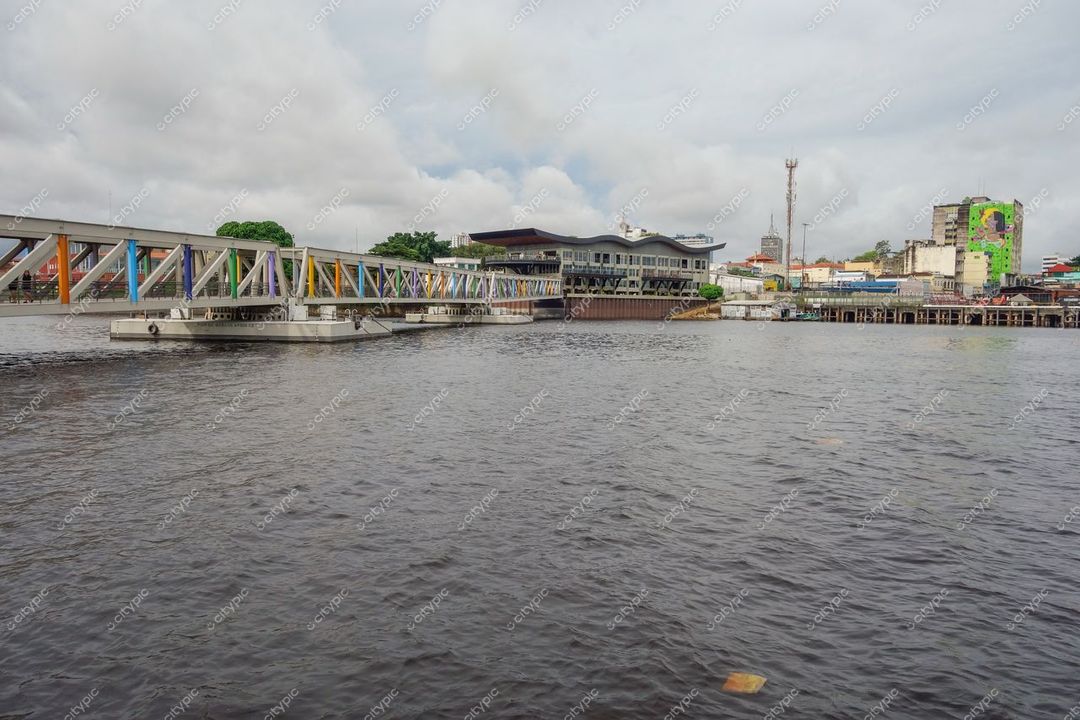 Manaus, Amazonas, vista do rio com píer moderno e edifício contemporâneo sob céu parcialmente nublado e vegetação urbana